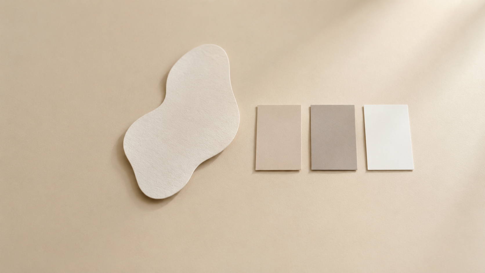 Un recorte de papel liso de un objeto sin etiqueta colocado sobre una superficie pálida y lisa junto a tres muestras de color en blanco