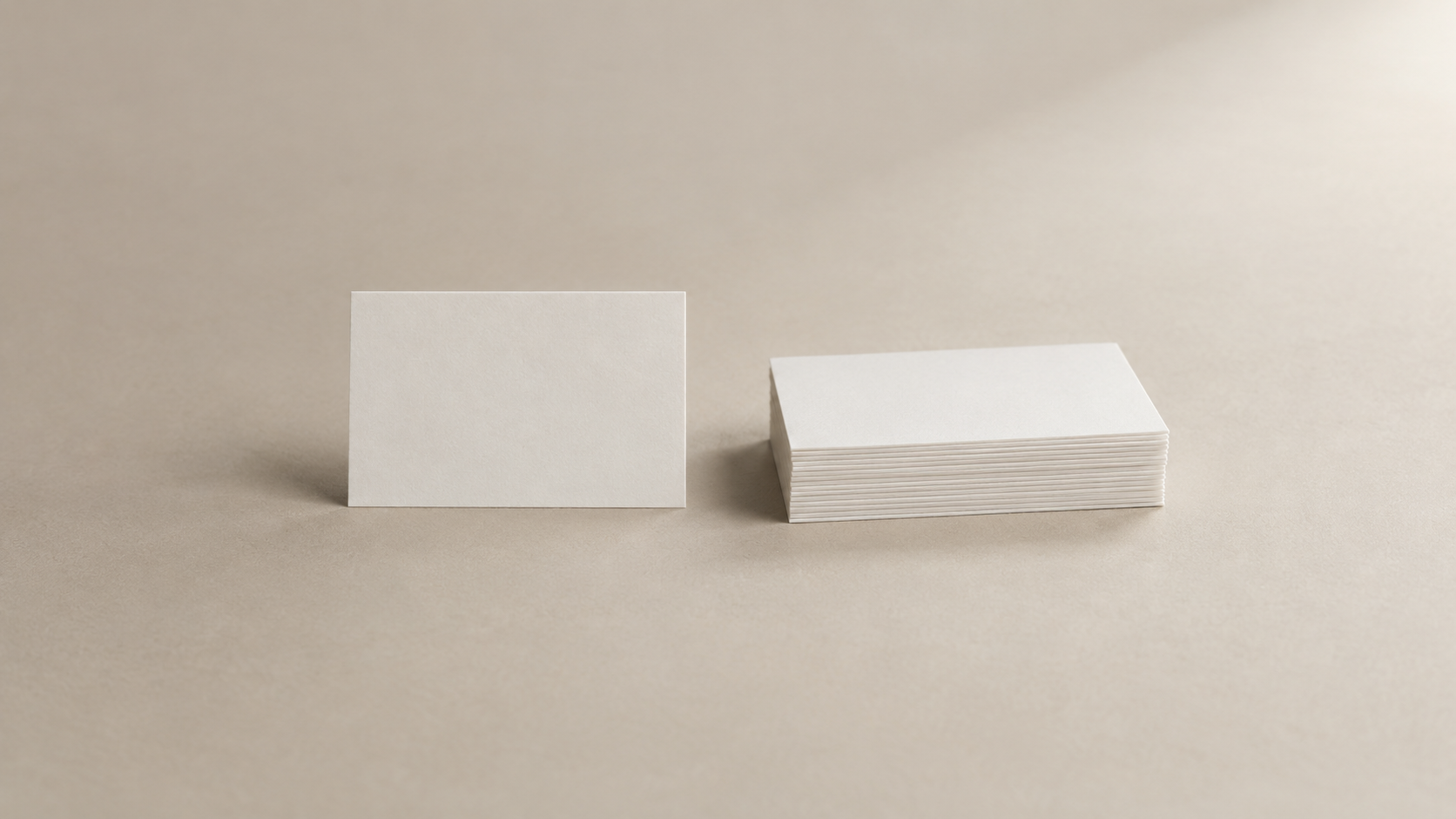 Una única tarjeta lisa ligeramente separada de una pila ordenada de tarjetas en blanco sobre una superficie neutra
