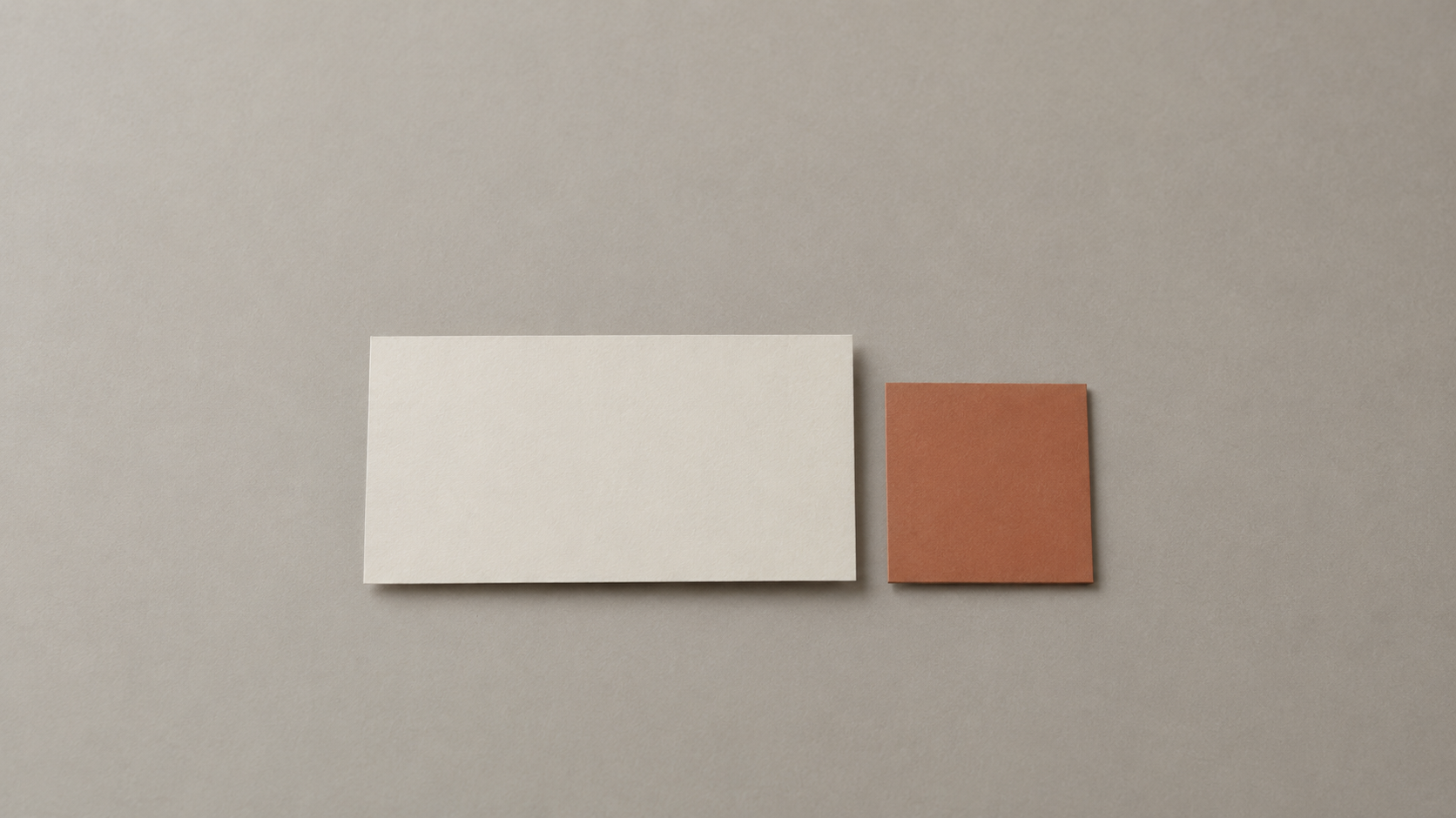 Una única tarjeta en blanco colocada sobre una superficie neutra limpia junto a una pequeña muestra de color lisa