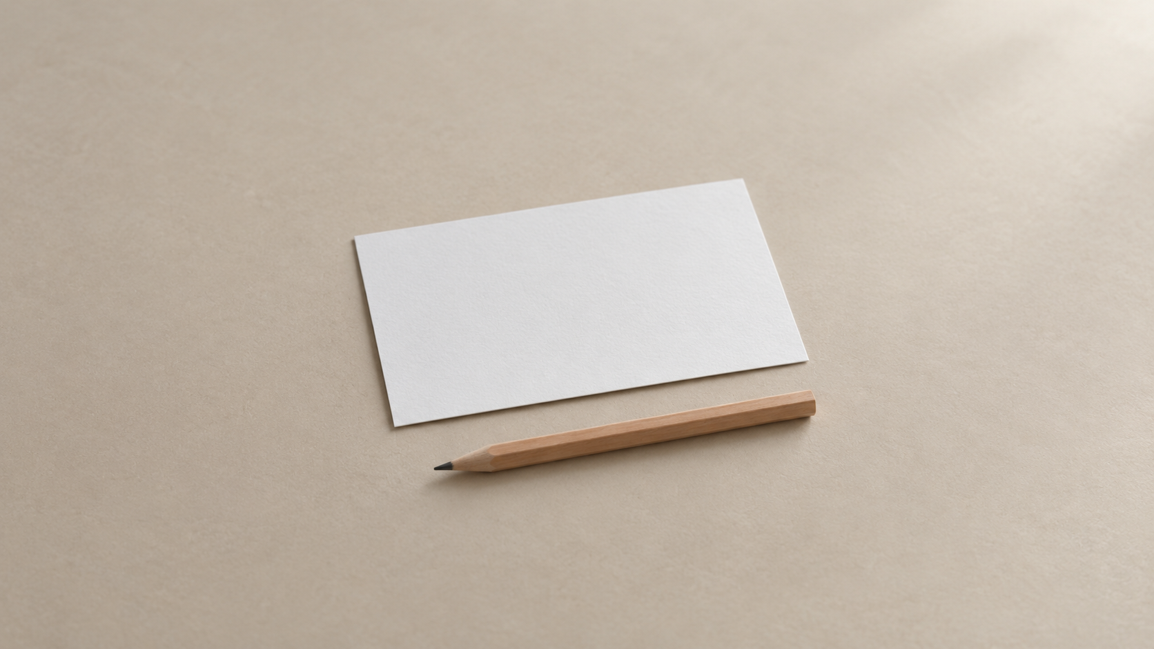 A single blank index card resting on a clean pale surface beside a short pencil, ready for a written brief